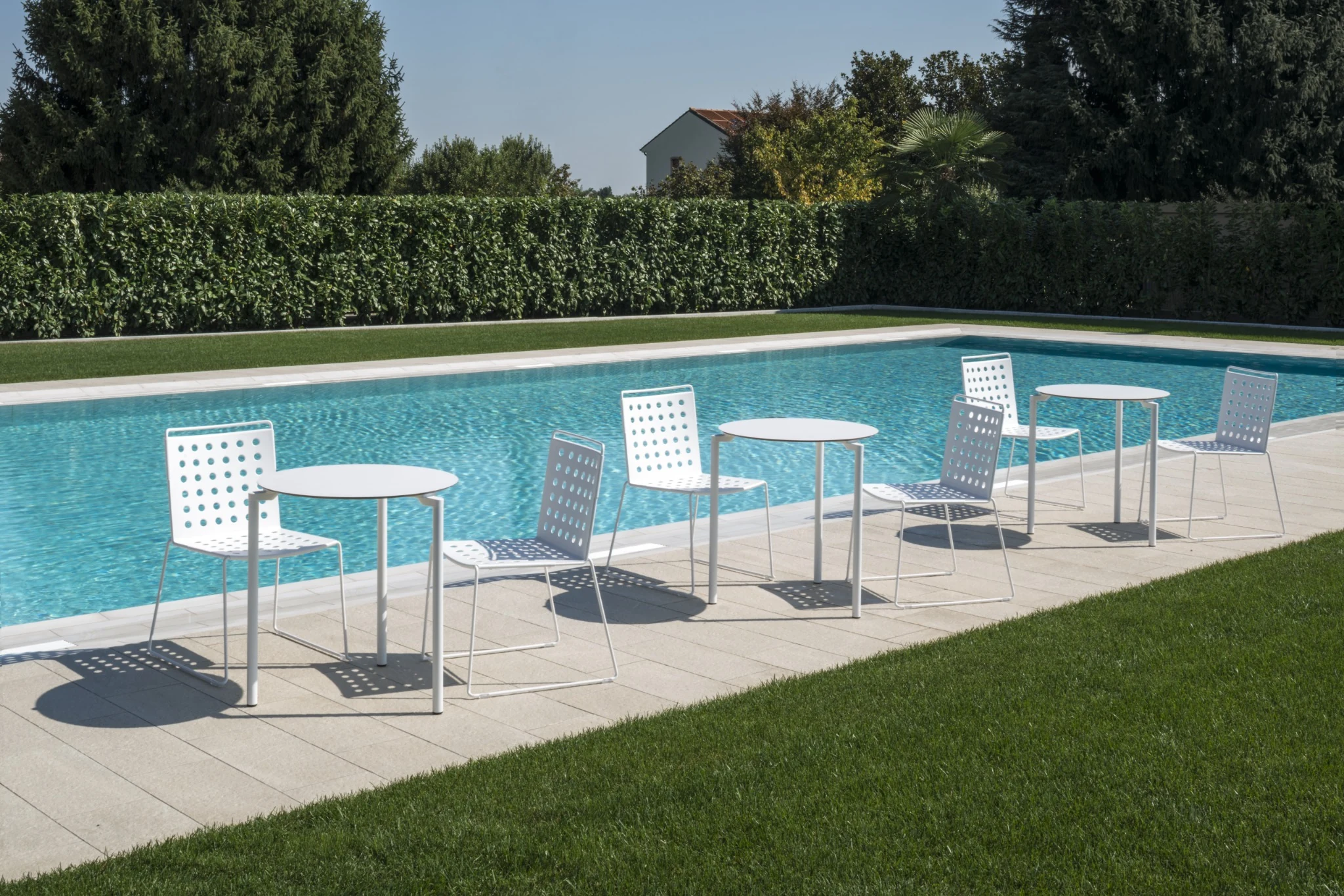 White Busy chairs around a long table on a covered outdoor terrace