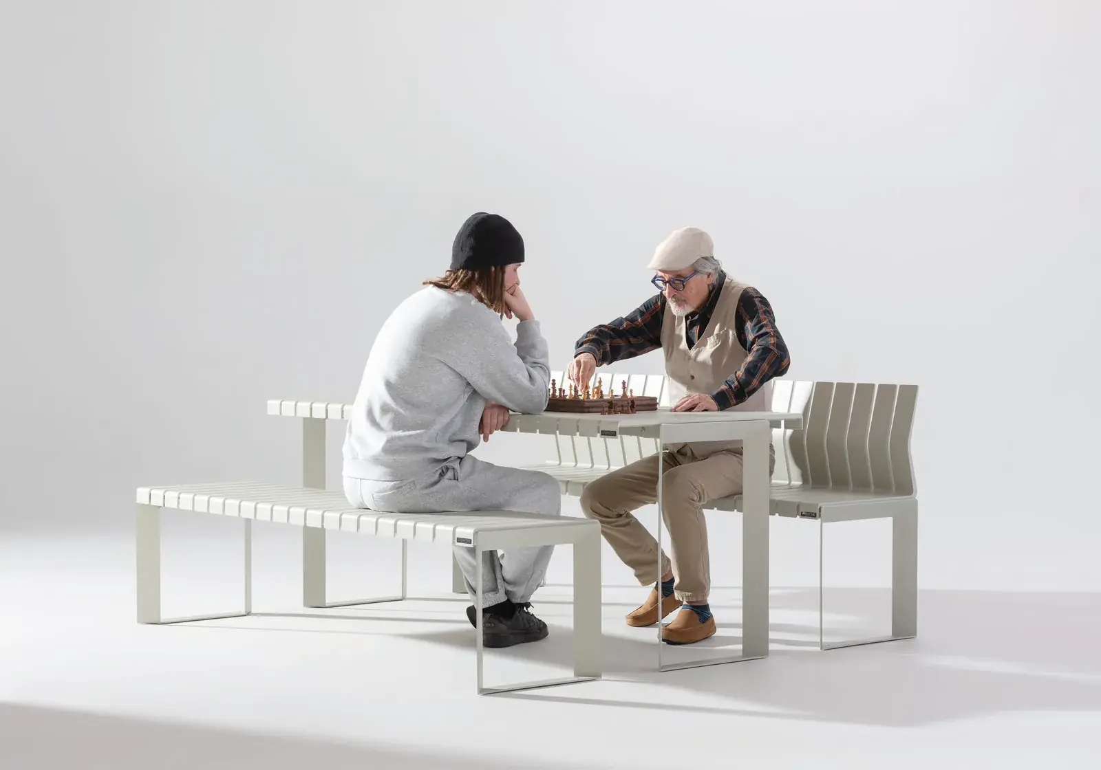 Two men playing chess at a white Liberty.080 table